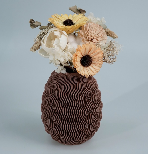 Elegant brown 3D-printed WAVE VASE with a wavy, ripple-like surface, filled with light-colored dried flowers. A sophisticated and artistic 3D print idea for wife that adds a refined touch to her decor.
