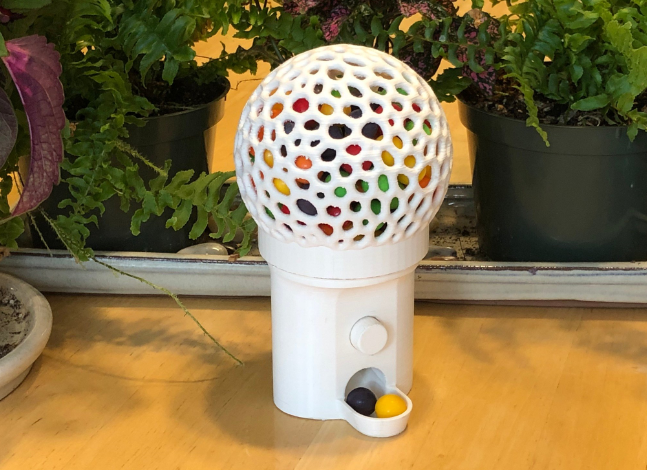 3D-printed white gumball machine with a perforated globe and colorful gumballs inside, a functional and nostalgic project for 3D printing.