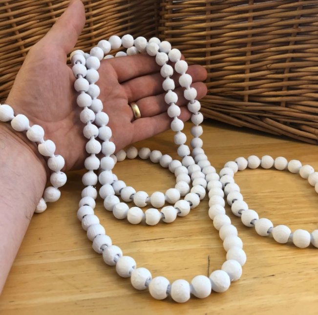 A photo showcasing a handmade, 3D-printed set of white beaded necklaces and bracelets. The beads are uniform in shape and texture, giving the accessories a clean, minimalist aesthetic. The items are displayed on a wooden surface, with a woven basket in the background, emphasizing a rustic, artisanal vibe.






