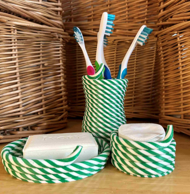 A set of 3D-printed bathroom accessories in a green and white striped design, featuring a toothbrush holder, soap dish, and a small container. These stylish and functional pieces showcase the creative potential of 3D printing for home organization.