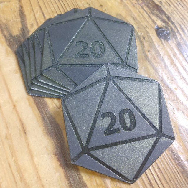 A set of 3D-printed coasters inspired by a D20 die design, featuring a metallic finish and the number '20' prominently displayed. These coasters are perfect for tabletop gamers looking to bring a bit of their favorite game to everyday use.