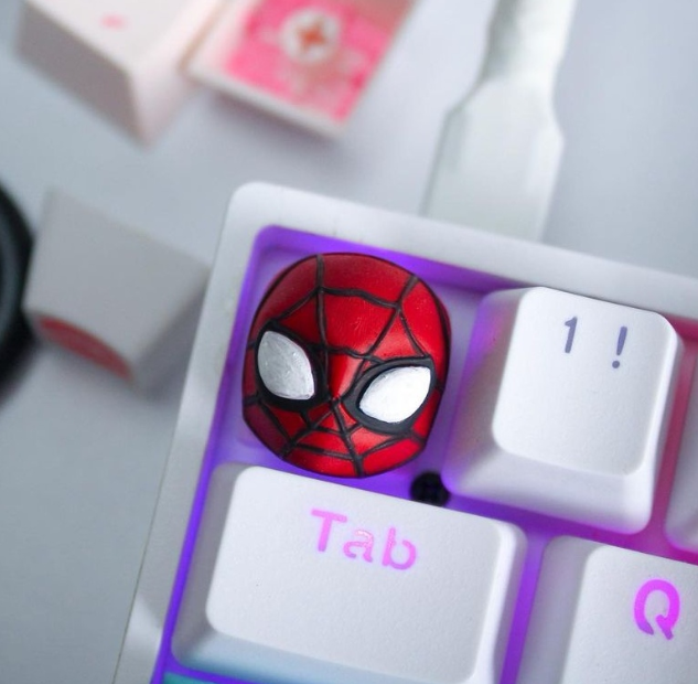 A custom keycap featuring a detailed red and black webbed mask design with white eyes, perfectly fitted on a mechanical keyboard. This playful and unique accessory adds personality and creativity to any keyboard setup.