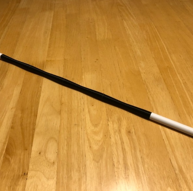  A sleek black-and-white 3D-printed pointer resting on a wooden table.