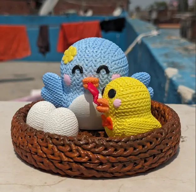 一隻藍色母鳥與黃色小雞坐在編織鳥巢裡，旁邊有白色鳥蛋，呈現溫馨的家庭時刻。